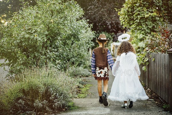 Sisters wearing Halloween costumes on sidewalk