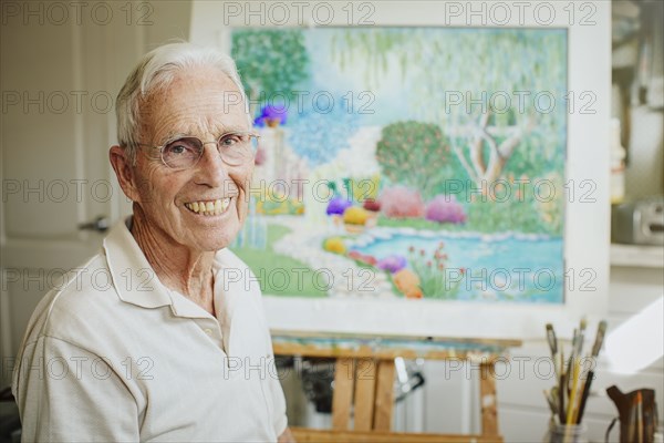 Caucasian artist smiling with painting in studio