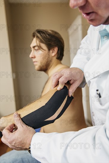 Caucasian doctor applying tape to elbow of patient