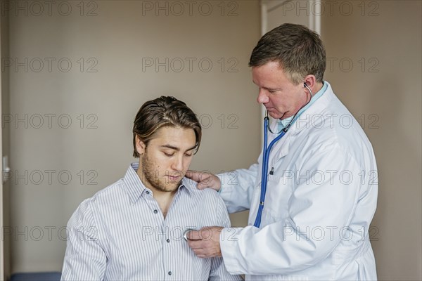 Caucasian doctor listening to heartbeat of patient