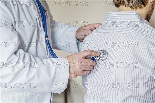 Caucasian doctor listening to heartbeat of patient