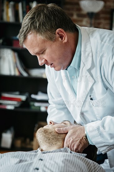 Caucasian doctor adjusting neck of patient