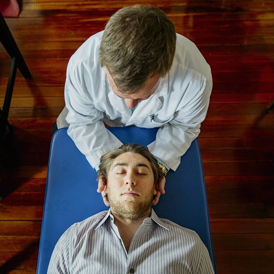 Caucasian doctor adjusting neck of patient