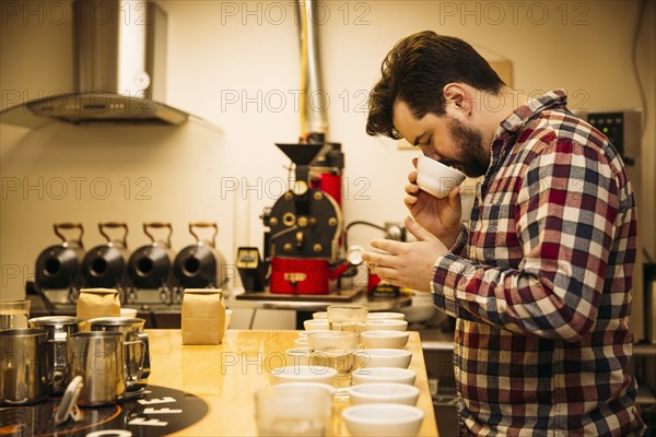 Caucasian barista tasting coffee in coffee shop