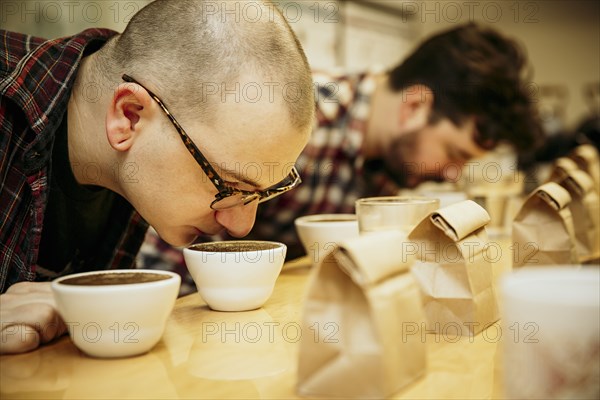 Caucasian baristas smelling coffee in cups