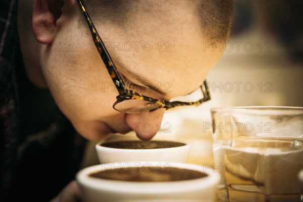 Caucasian barista smelling coffee in cup
