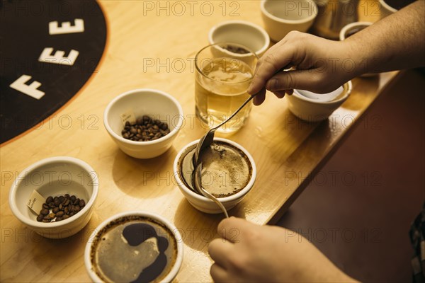 Caucasian barista tasting coffee in coffee shop