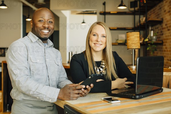 Waiter and businesswoman using technology in cafe