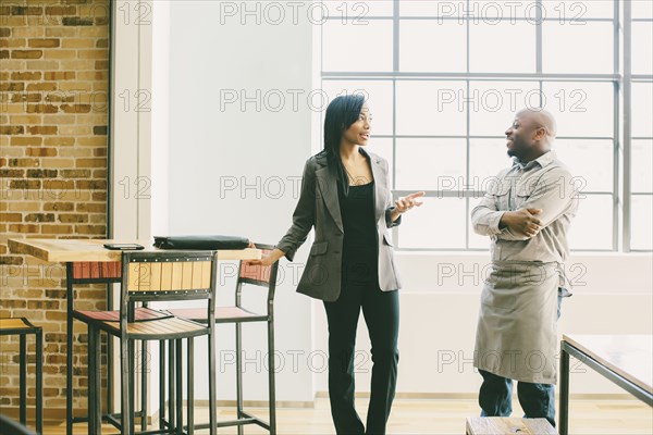 Black businesswoman and waiter talking in cafe