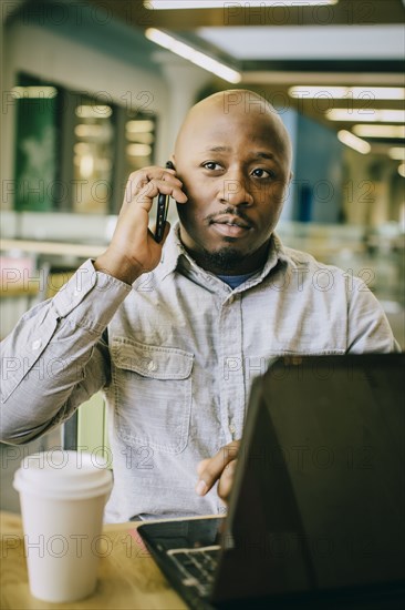 Black businessman talking on cell phone in cafe