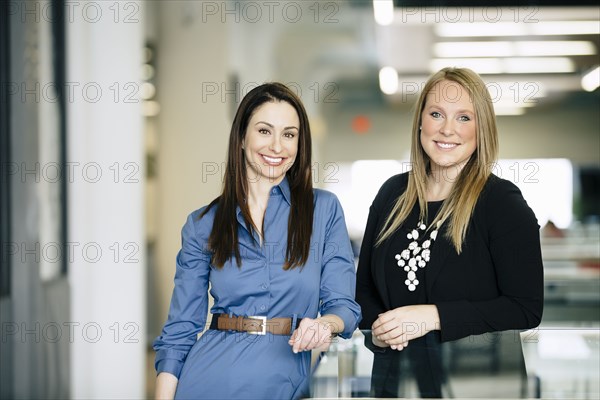 Caucasian businesswomen smiling in office