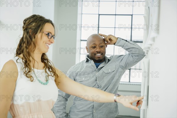 Business people examining paperwork on office wall