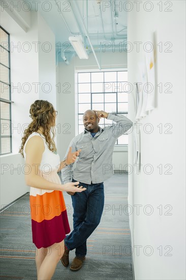 Business people discussing paperwork on office wall