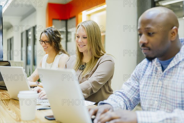 Business people working on laptops in office meeting