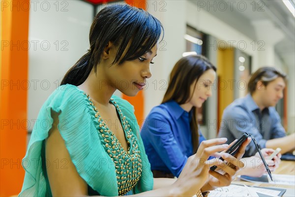 Businesswoman using cell phone in office meeting