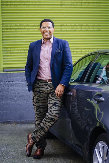 Stylish Mixed race businessman leaning on car