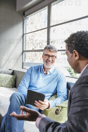 Businessmen using digital tablet in office lobby