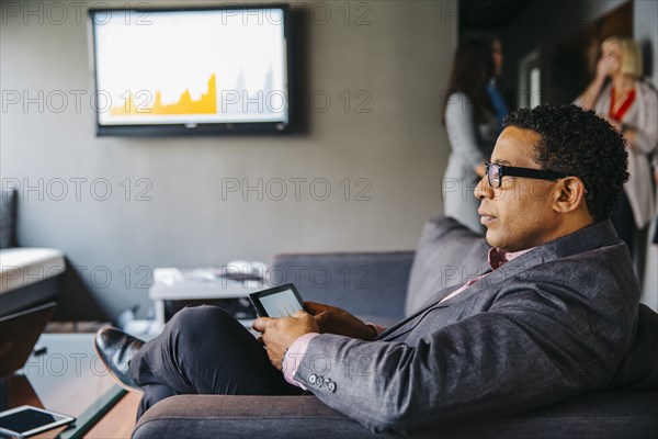 Mixed race businessman using digital tablet in office lounge