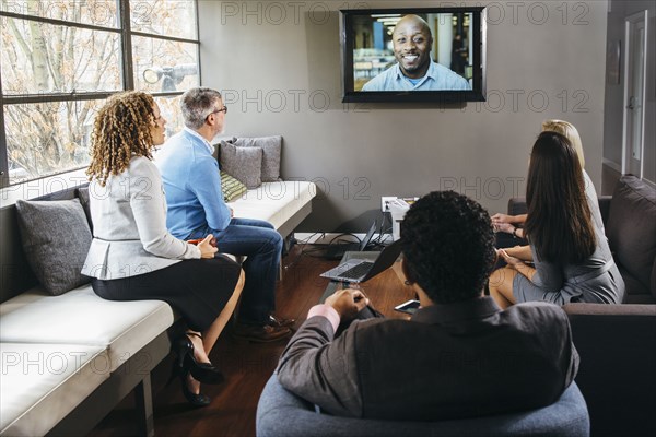 Business people watching teleconference in office meeting