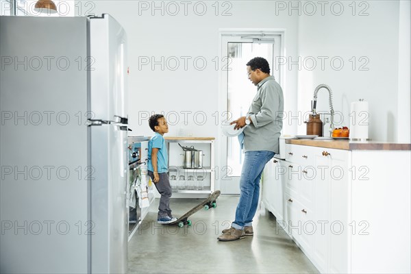 Father scolding son for skateboarding in kitchen