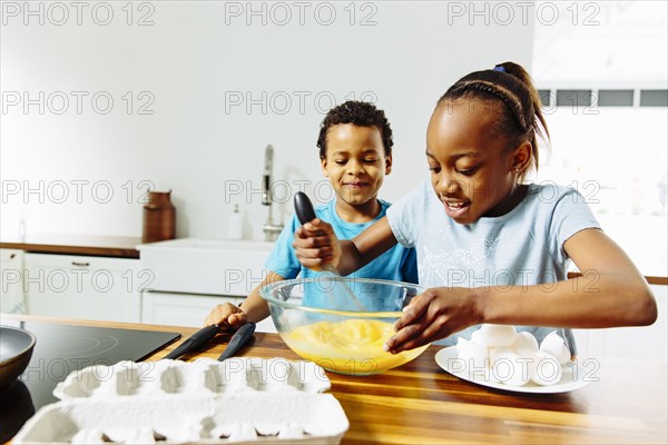 Brother and sister cooking breakfast in kitchen