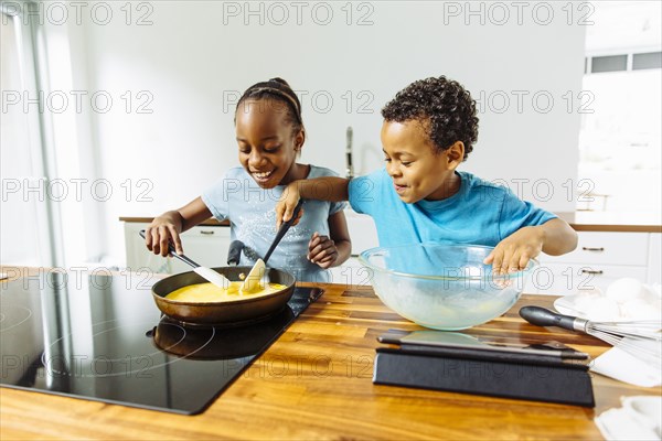 Brother and sister cooking breakfast in kitchen