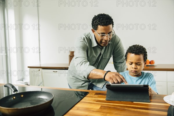 Father and son cooking with digital tablet in kitchen