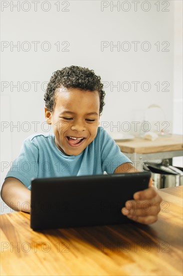 Mixed race boy using digital tablet in kitchen