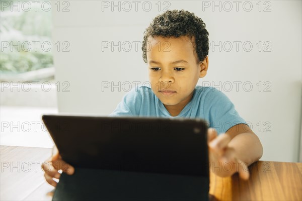 Mixed race boy using digital tablet at table