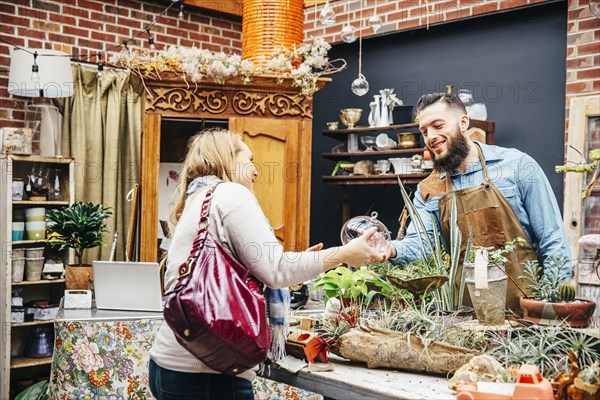 Caucasian employee helping customer in plant nursery