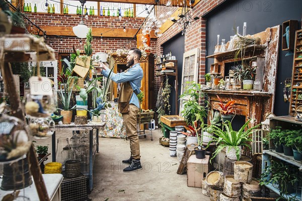 Caucasian employee watering plants in nursery