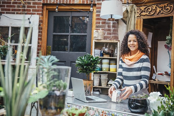 Mixed race employee using laptop in plant nursery