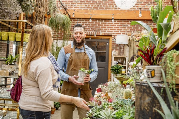 Caucasian employee helping customer in plant nursery