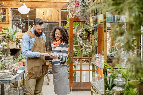 Employees using digital tablet in plant nursery