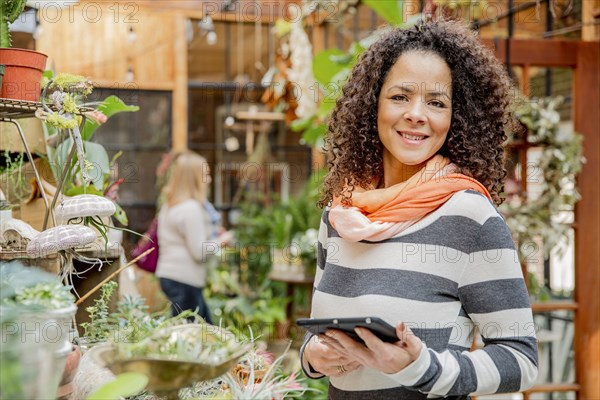 Mixed race employee using digital tablet in plant nursery