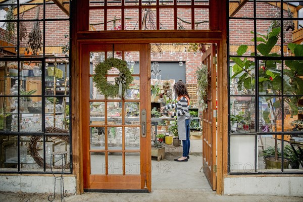 Mixed race employee working beyond doorway in plant nursery