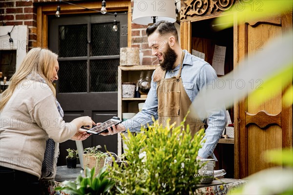 Employee helping customer with digital tablet in store