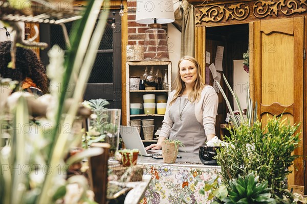 Caucasian employee using laptop in plant nursery