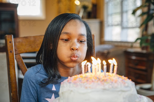 Black girl blowing out candles on birthday cake