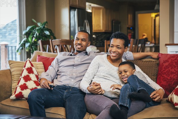 Black family watching television on sofa