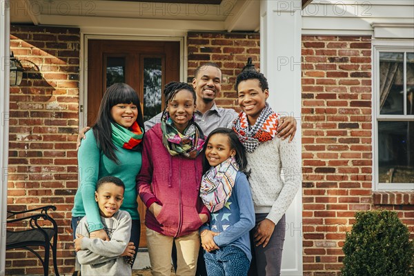 Black family smiling outside house
