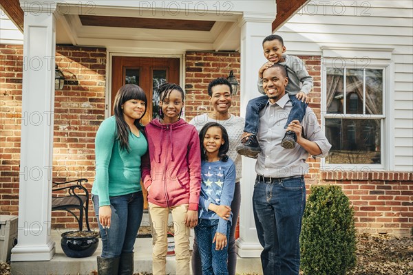 Black family smiling outside house