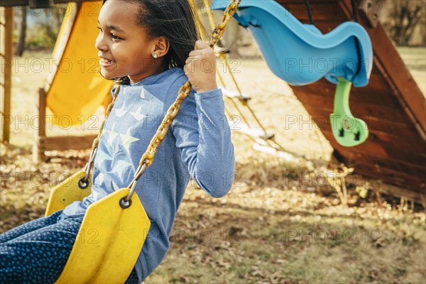 Black girl sitting on swing set