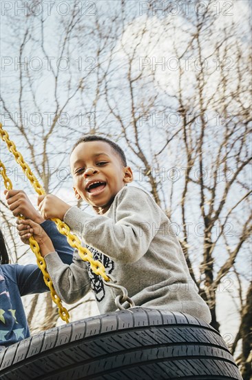 Black boy playing on tire swing