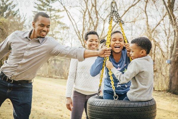 Black family playing on tire swing