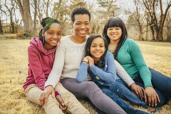 Black mother and daughters sitting outdoors