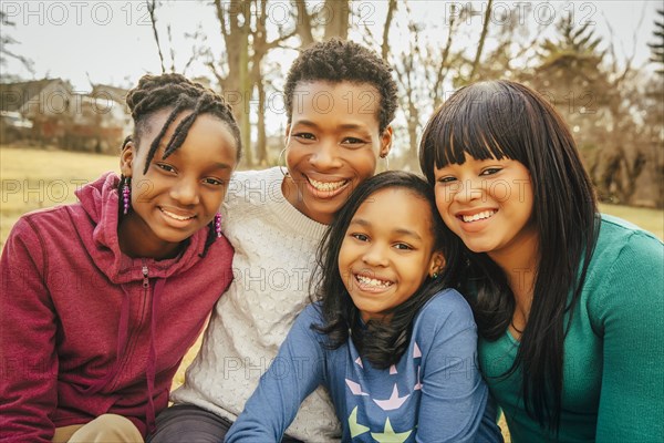 Black mother and daughters sitting outdoors