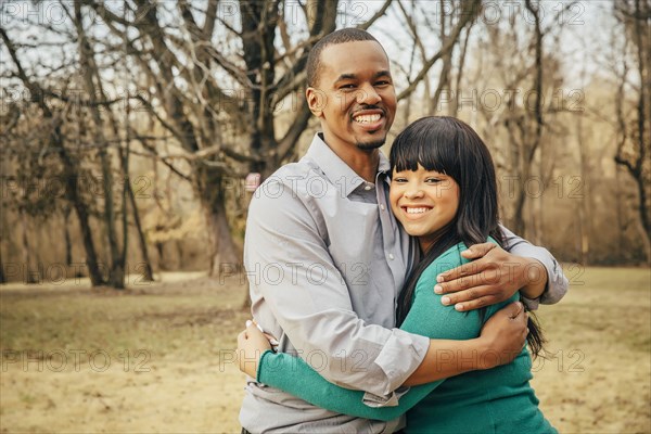 Black father and daughter hugging outdoors