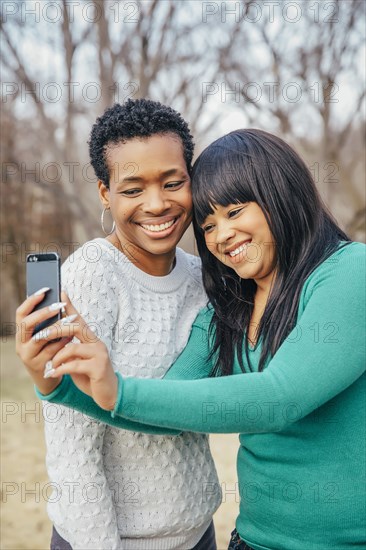 Black mother and daughter taking selfie outdoors