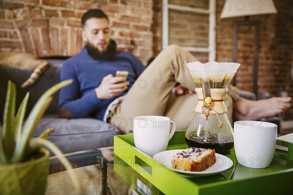 Man using cell phone with breakfast in living room